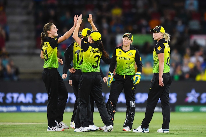 An Australian bowler high fives teammates after taking a wicket at the Women's T20 World Cup.