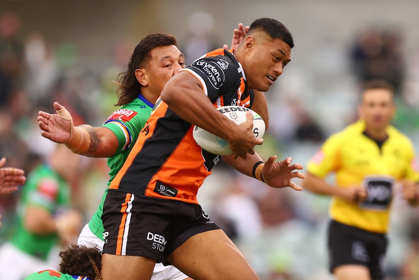 Stefano Utoikamanu fends off a Rabbitohs player.