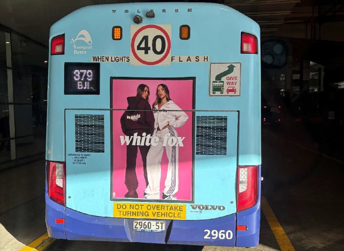 A bus advertisement showing two models in tracksuits with a four stripe design.