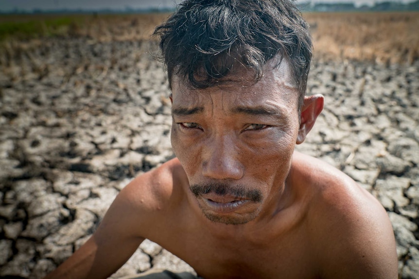 A close-up image of Rice farmer Ampir, standing in a dry paddy