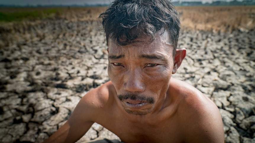 A close-up image of Rice farmer Ampir, standing in a dry paddy