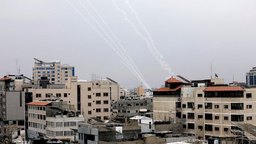 Smoke trails in the sky above a city made up of several multi-storey buildings