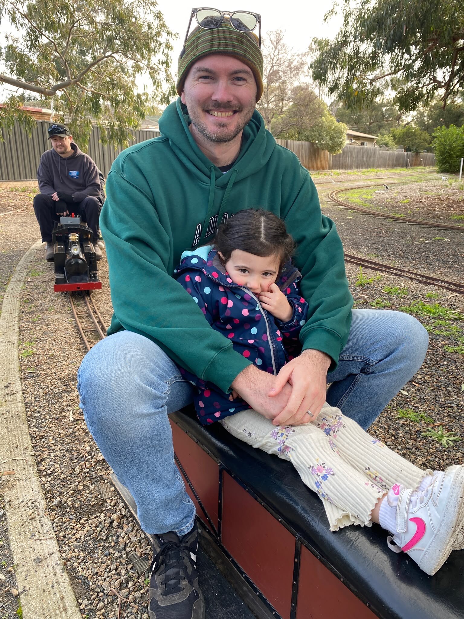 A man sitting outside with his arms around a young child.