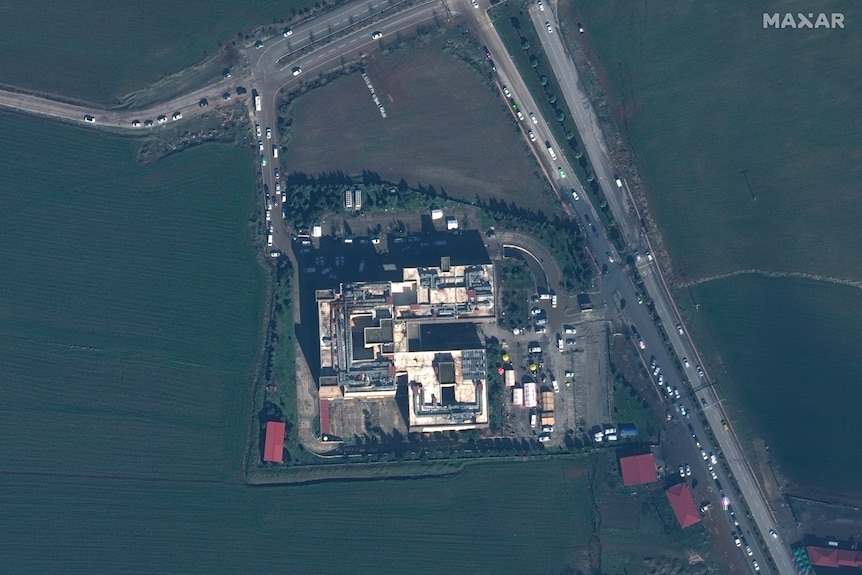 An overhead shot of buildings and roads surrounded by green fields.