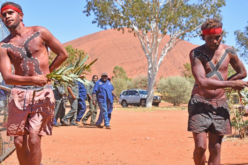 Two aboriginal men painted, dancing on community.