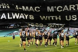 Fitting tribute ... Port Adelaide's players run through the banner during the memorial service for John McCarthy.