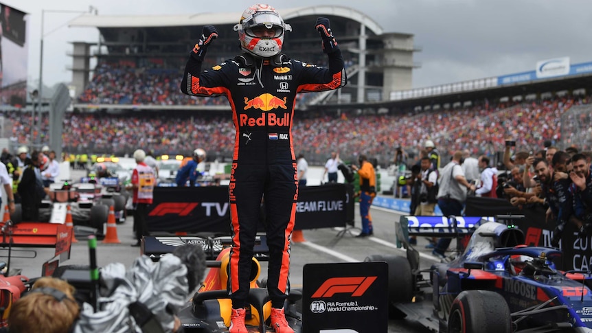 A jubilant Max Verstappen stands on his car and pumps his fist after winning the German F1 grand prix.