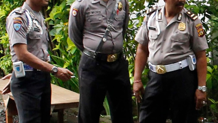Three Balinese policemen stand together.