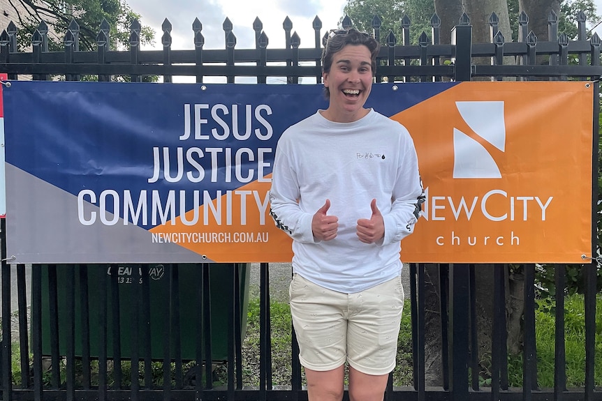 Steff Fenton gives a 'thumbs up' with the banner for their Church.