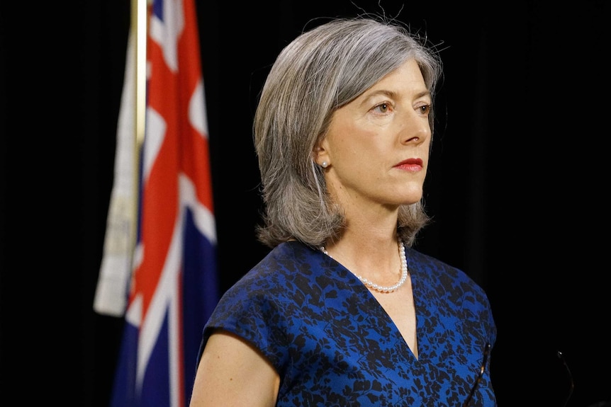 Nicola Spurrier looking away from the camera with an Australian flag in the background.