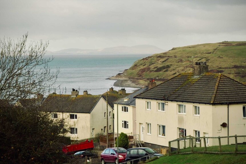 Houses in Workington with the sea and a grassy headland in the background.