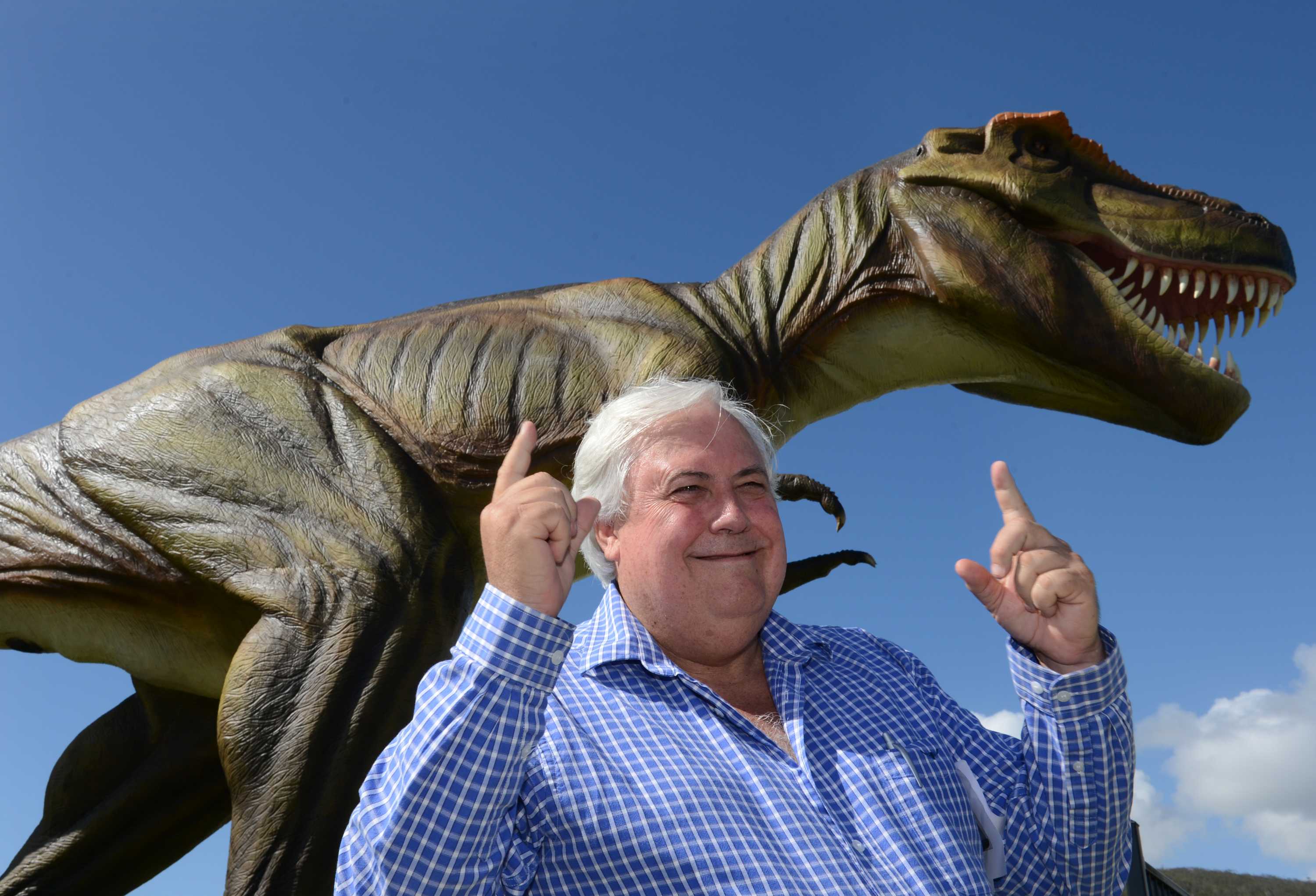 Clive Palmer poses for a photograph in front of a statue of Jeff the dinosaur.