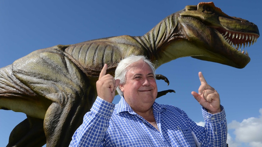 Clive Palmer poses for a photograph in front of a statue of Jeff the dinosaur.