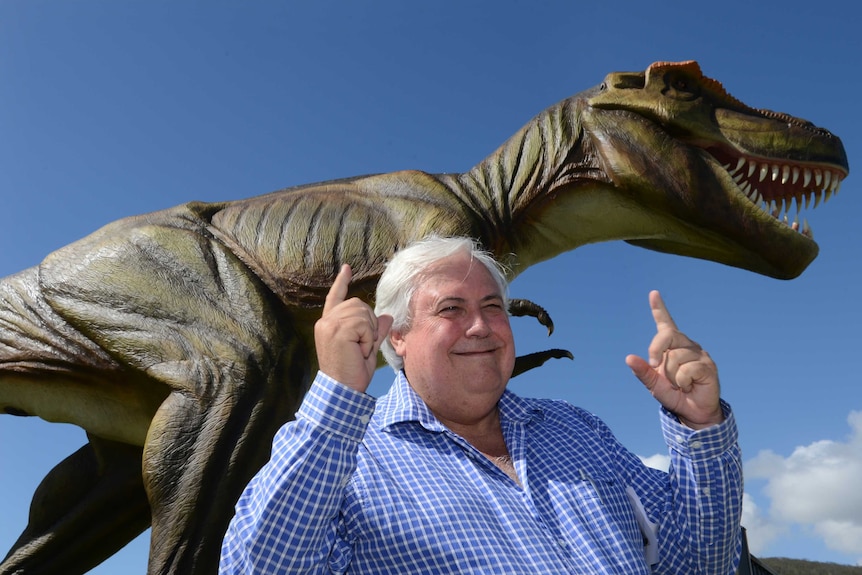 Clive Palmer poses for a photograph in front of a statue of Jeff the dinosaur.