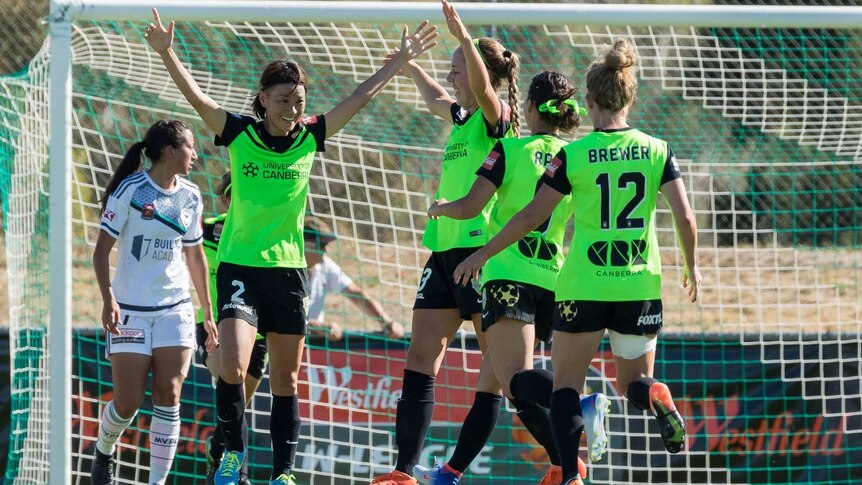 Canberra United players celebrate after a goal against Melbourne Victory