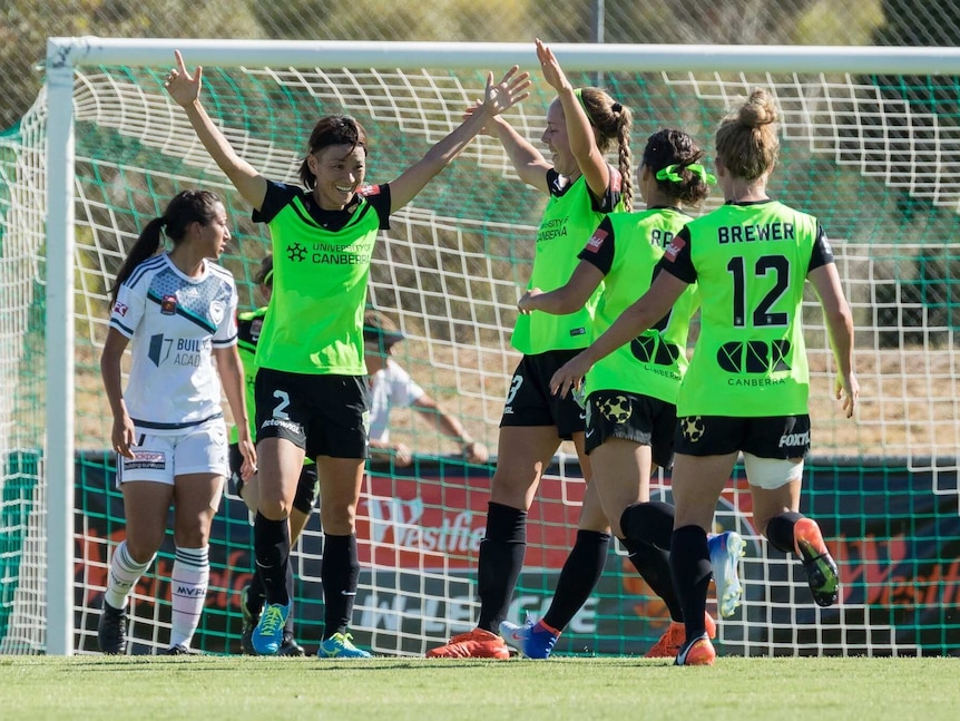 Canberra United players celebrate after a goal against Melbourne Victory