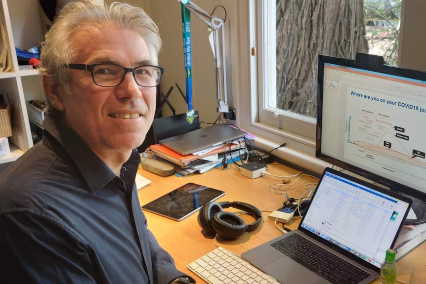 Richard Osborne sits at a desk, with a computer displaying COVID-19 data.