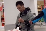 A man wearing jacket standing in supermarket's check out cashier