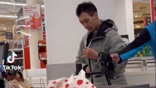 A man wearing jacket standing in supermarket's check out cashier