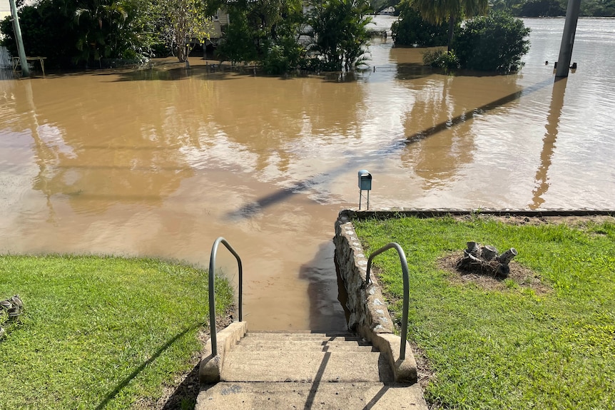 Flood water surrounds a staircase leading to a house