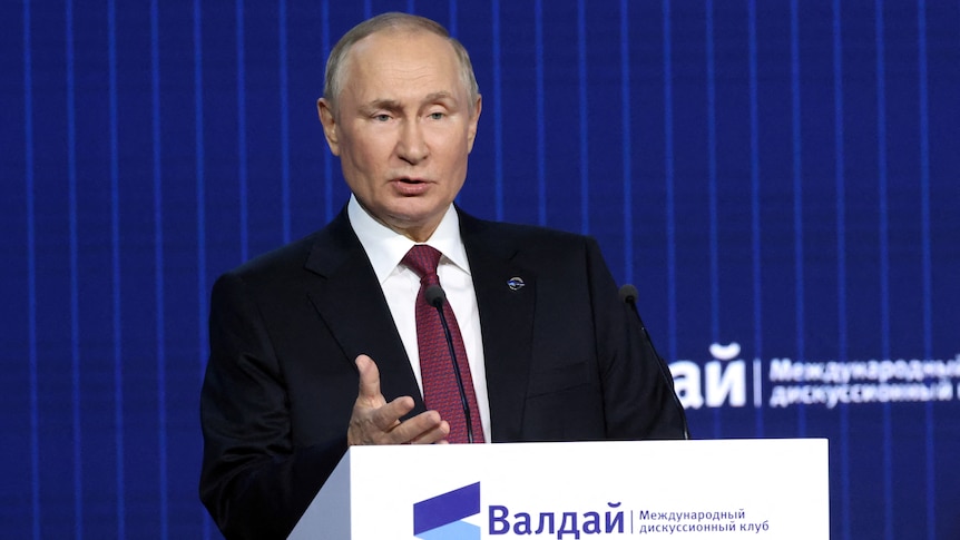 Russian President Vladmir Putin speaking from lectern.
