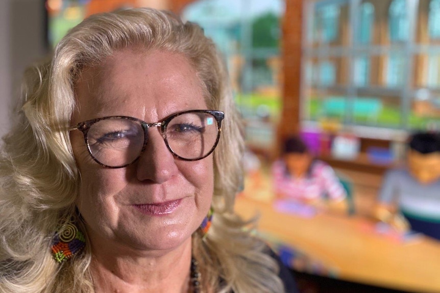 Head shot of Susan Ledger, with a virtual classroom in the background.