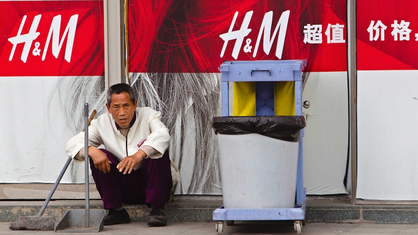 A cleaner sits outside an H&M store in China.