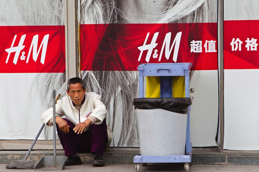 A cleaner sits outside an H&M store in China.