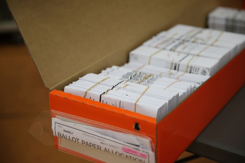 Orange cardboard box contains bundles of printed pamphlets. The box is labelled "Durack ballot paper allocation"