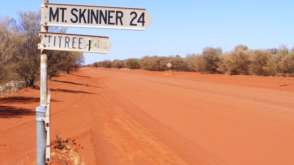 A sign pointing to Mt Skinner station, red dirt in the background