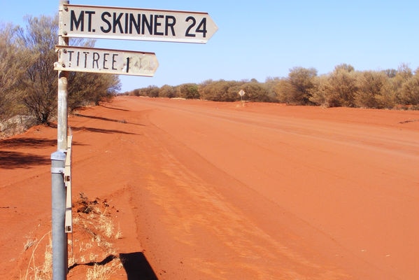 A sign pointing to Mt Skinner station, red dirt in the background