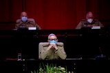 raul castro sits with his hands clasped wearing a mask