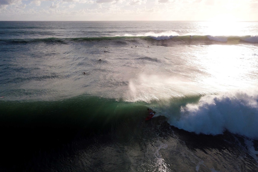 An aerial photo of surfers with a number of waves coming.