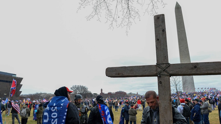 A man holds a large wooden cross near the Washington Monument during a rally on January 6, 2021.