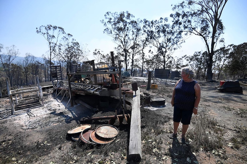 Resident Jeanette Schwindt looks at damage to her property at Mount Larcom after bushfires.