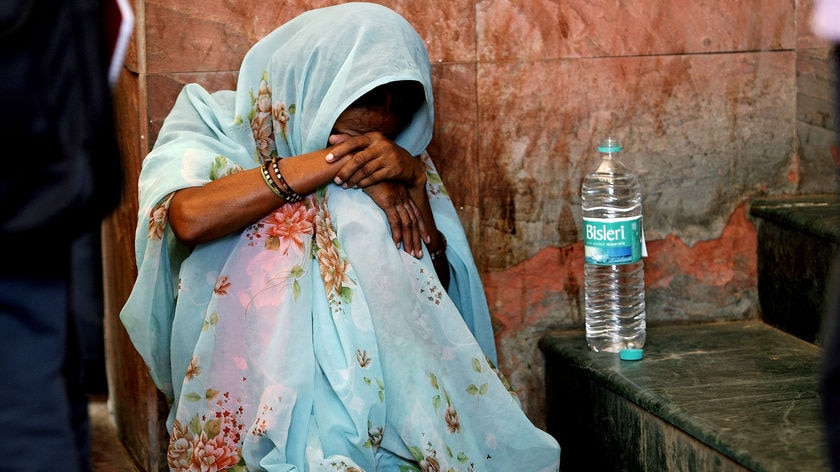 Indian woman mourns after Delhi market bombing, head down, unindentied