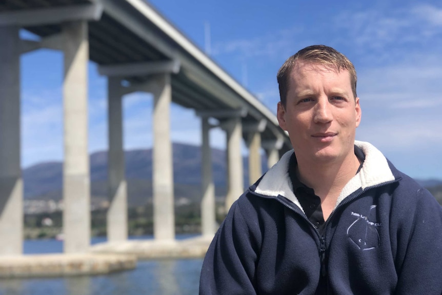 Diver Andrew Bain stands in front of the Tasman Bridge.