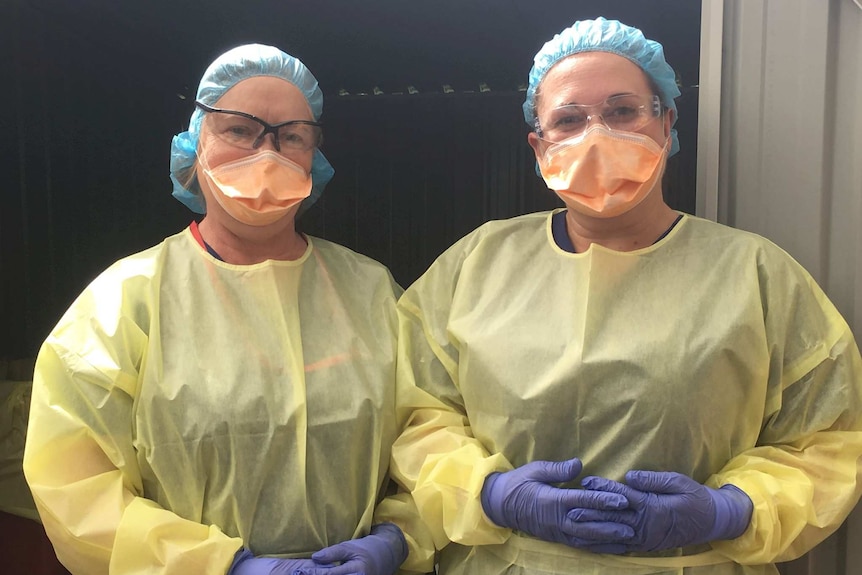 Two women in protective equipment such as masks, goggles, aprons, gloves