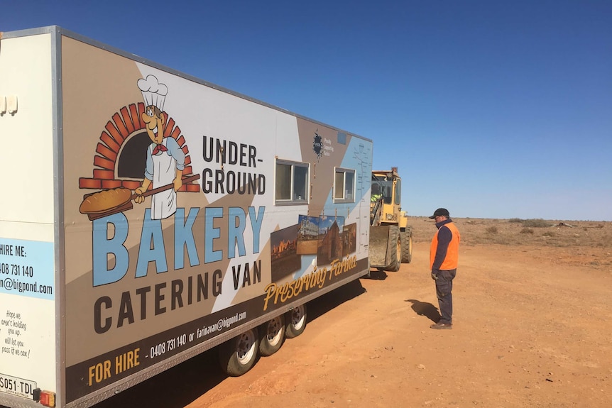 A man stands beside a large mobile bakery truck