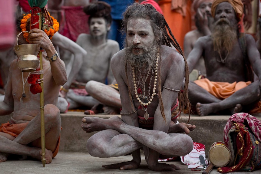 A group of Indian holy men perform sitting yoga poses.