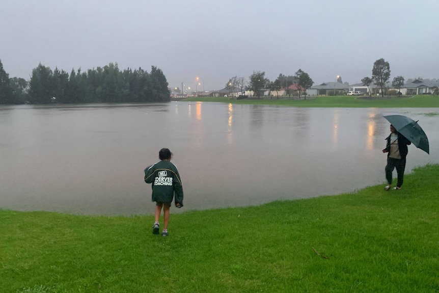 Two young people on the edge of an oval that is covered in water.