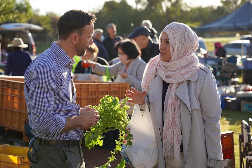 Vince Connelly speaks to a constituent wearing a hijab in a market setting