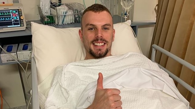 Olympic swimming champion Kyle Chalmers in a hospital bed giving the thumbs up.