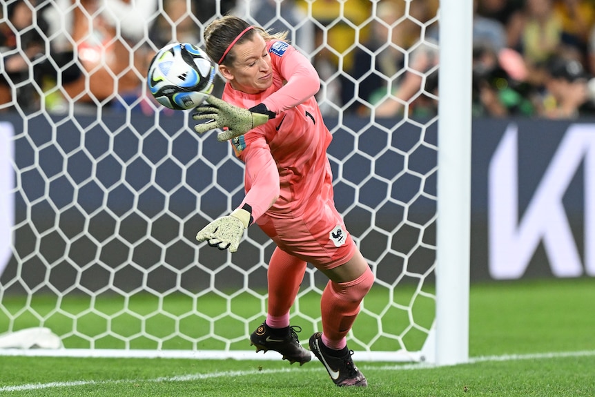 A soccer ball bursts through the hands of France goalkeeper Solene Durand in a penalty shootout against Australia.