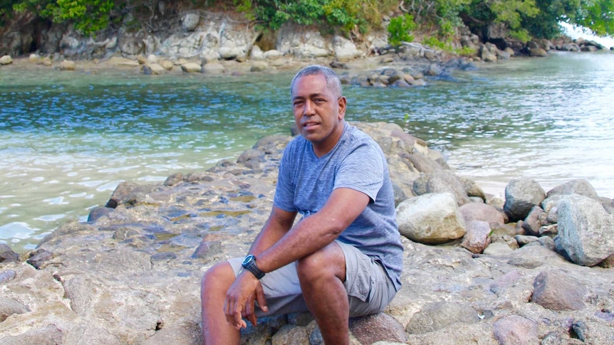 A Fijian man smiles in a black shirt with a white pattern.