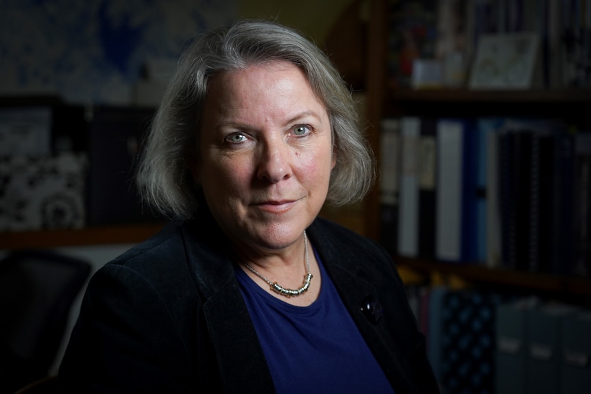 Elizabeth Handsley sitting in a dark room, looking at the camera.