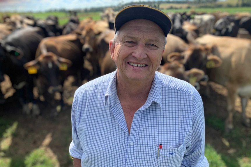 John smiles with cattle behind him.