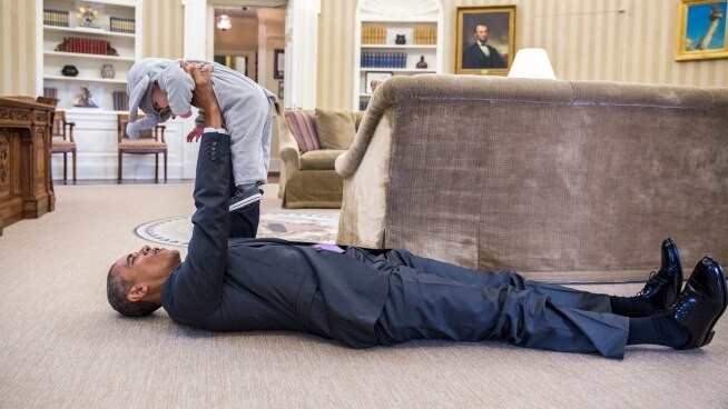 President Barack Obama holds up a young child in an elephant costume.
