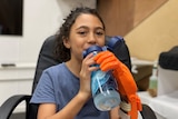 young girl holds water bottle with prosthetic hand 