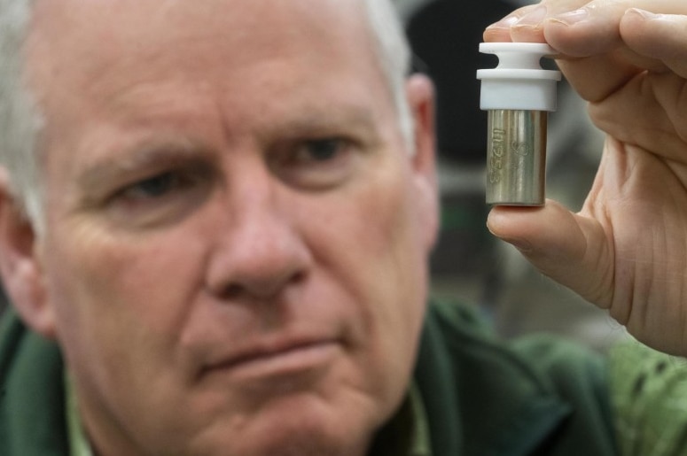 Professor Trevor Ireland holds a vial of moon dust.